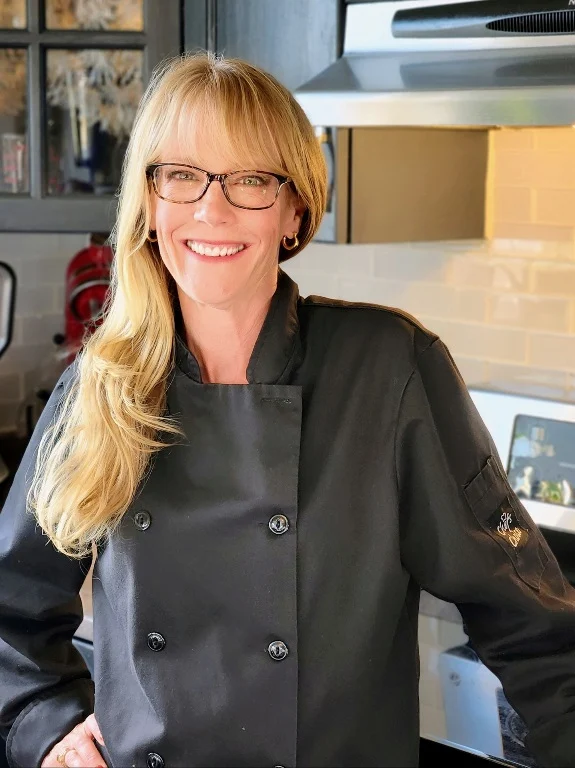 Chef Kate in her chef's jacket, smiling in her Nova Scotia kitchen