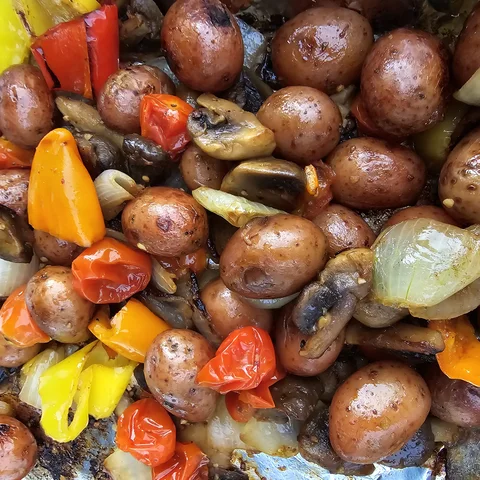 Sheet pan of roasted baby potatoes, peppers, mushrooms, and onions